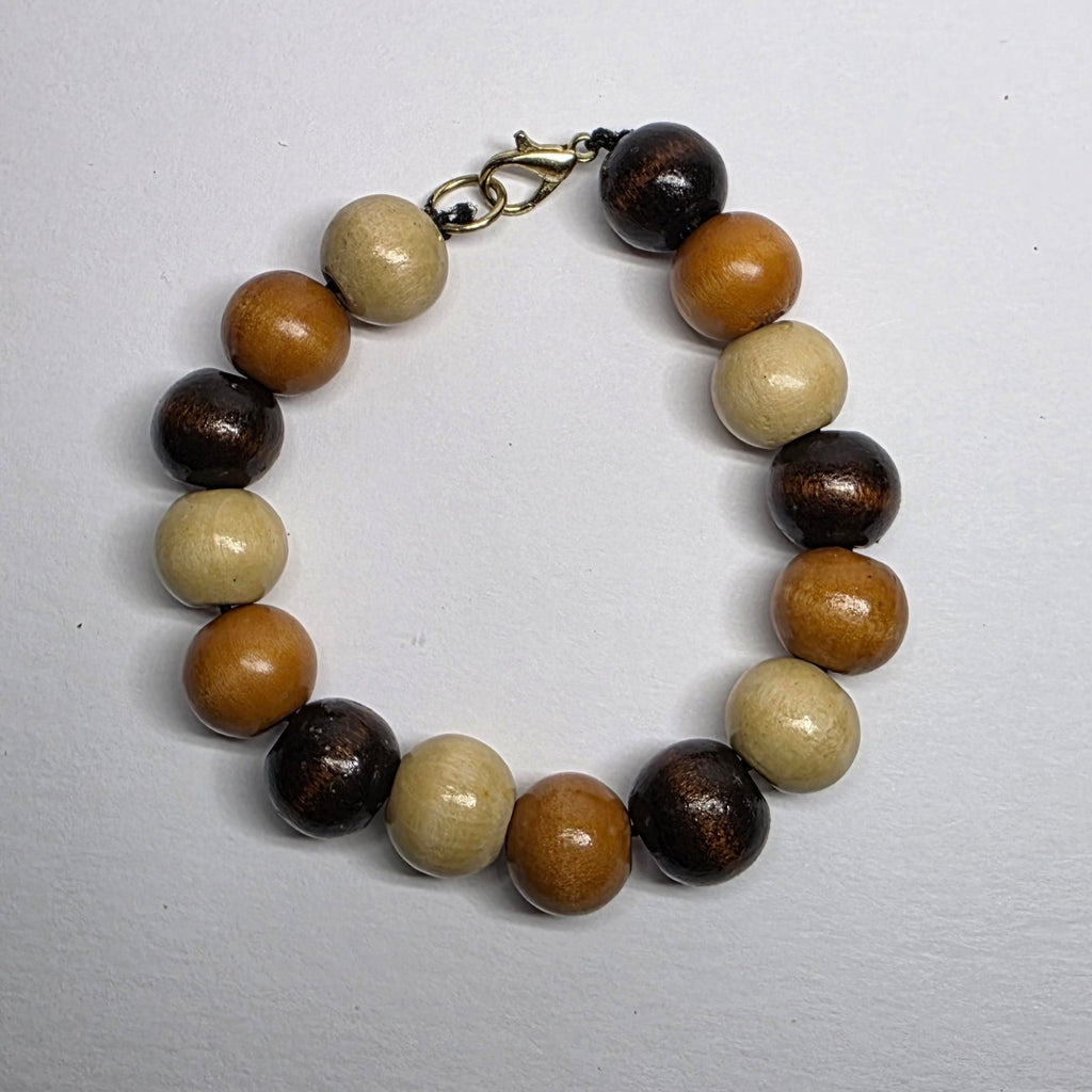 Beaded bracelet with brown, beige, and black beads on a light gray background
