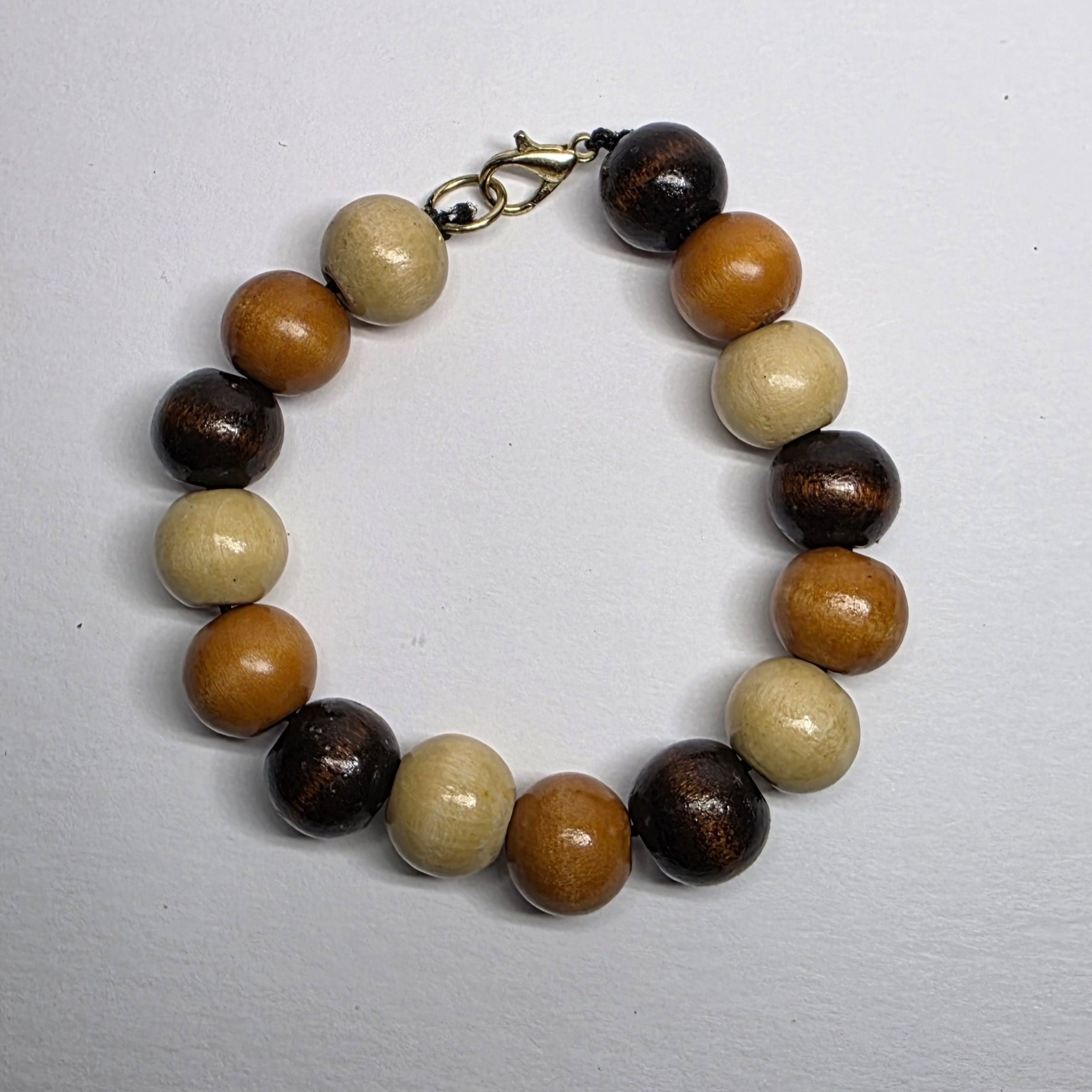 Beaded bracelet with brown, beige, and black beads on a light gray background