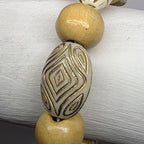 Beaded bracelet with decorative beads on a white cylindrical object against a gray background